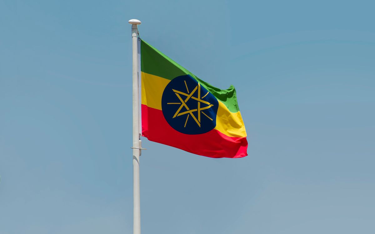 The Ethiopian national flag flying against a clear blue sky