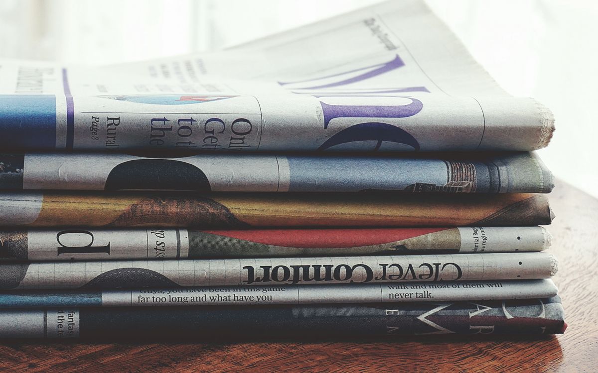 A stack of folded newspapers on a wooden table